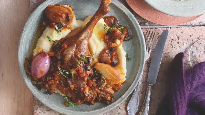 Muslo de ganso asado con ragú de verduras, champiñones y puré de apio