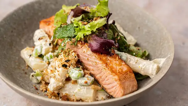 Creamy spring bowl with white asparagus, broad beans, salmon, and furikake crumbs