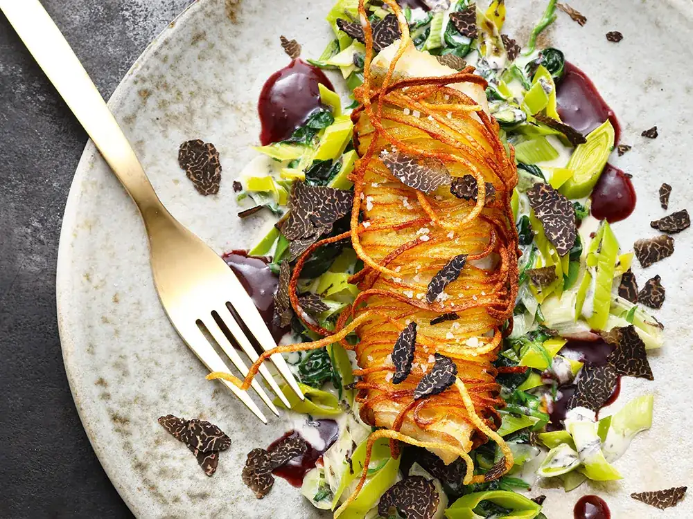 Pike-perch fillet in a potato crust on spinach and leek vegetables with truffle