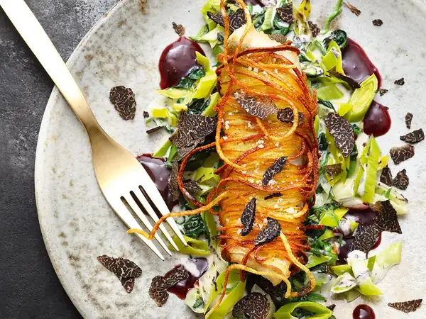 Pike-perch fillet in a potato crust on spinach and leek vegetables with truffle