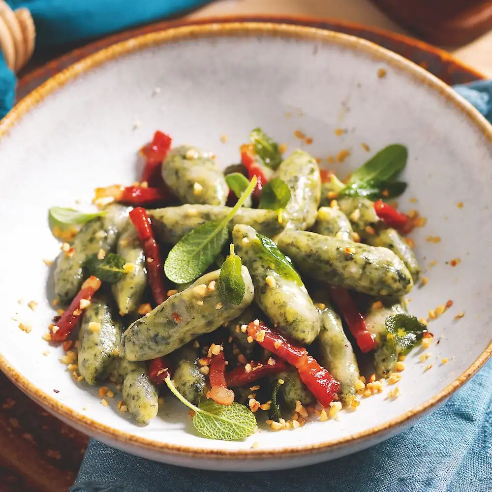 Herb gnocchi with butter, speck, and chopped hazelnuts