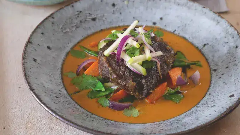 Veal on a spoon with curry sauce and vegetables