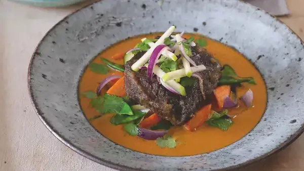 Veal on a spoon with curry sauce and vegetables