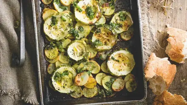 Baking dish with giant zucchini, potatoes and crushed herbs with garlic